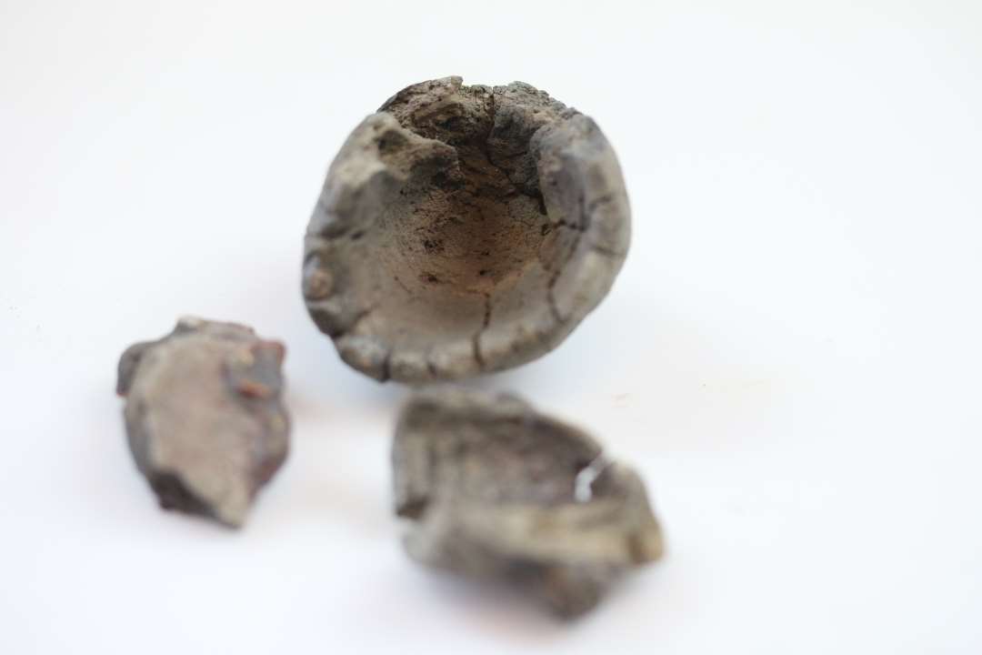 Dele til en digel og rester af yderlig en eller flere�den ene m�ler:�h�j 4,5 cm�diam. 3,5 cm�fastsmeltet slagge og rest af v�vning